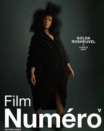 Fashion editorial shot featuring a woman in a black sculptural garment against a muted grey backdrop, promoting Film Numero Netherlands.
