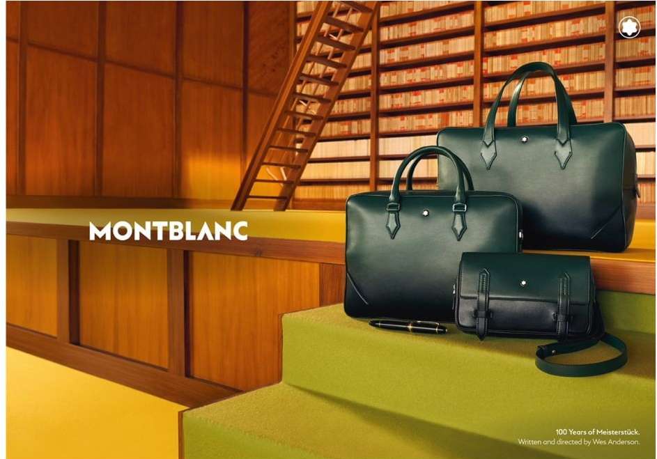 Montblanc advertisement with three dark green leather bags of different sizes arranged on lime green steps, library background.