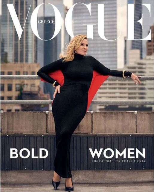 Magazine cover featuring an adult female model in a long black dress and red cape, posing on a rooftop with a city skyline backdrop.