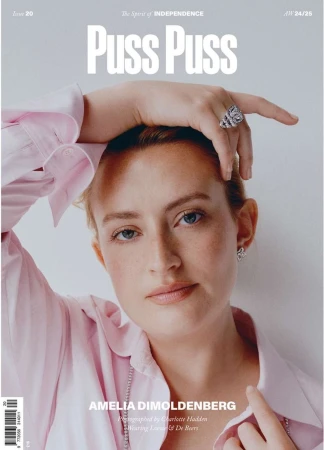 Magazine cover featuring a blonde woman with her hand on her head, wearing a pink collared shirt and jewelry, set against a light background.