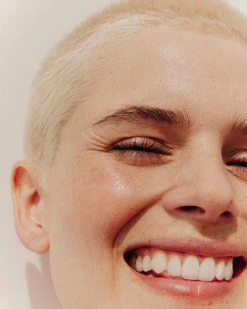 Close-up portrait of a smiling woman with short blonde buzzcut and visible freckles photographed in Paris by Charlotte Navio
