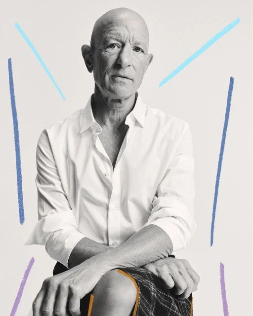 Bald man seated in a white button-down shirt and patterned skirt, captured in a medium shot with pastel graphic accents on a white background.