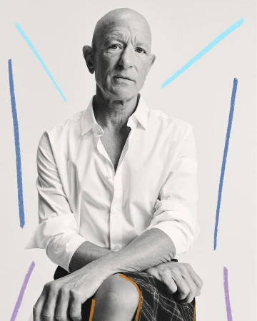 Bald man seated in a white button-down shirt and patterned skirt, captured in a medium shot with pastel graphic accents on a white background.