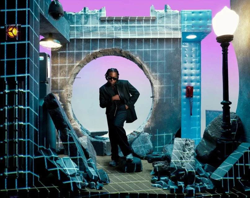 Man in suit poses in a futuristic tunnel with grid-like architecture and a vibrant pink sky, creating a surreal and modern scene.