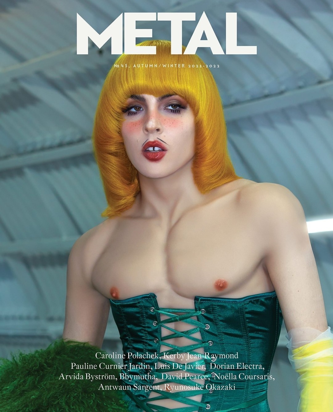 Magazine cover featuring a person in an emerald corset and yellow wig on a blurred background. Fashion editorial with creative styling.