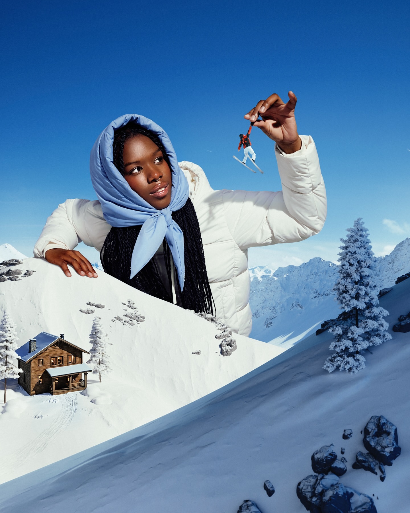 A dark-skinned woman in a puffy white jacket and blue scarf holds up a miniature skier in a surreal winter mountain scene.
