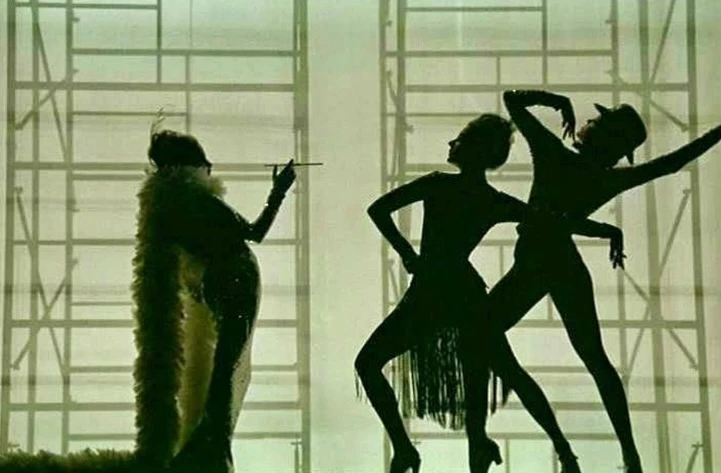 Three dancers in silhouette with geometric background. One adult female in a boa smoking, with two other dancers in motion.