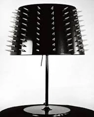 Black table lamp with rows of silver spikes covering the glossy lampshade, photographed by Charlotte Rutherford.
