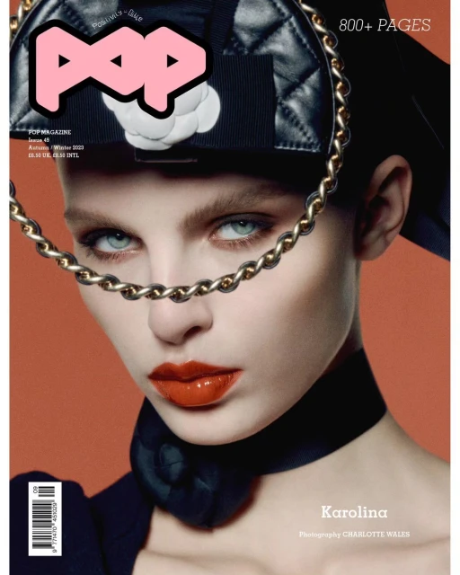 Magazine cover featuring a portrait of a young adult female model with orange lipstick and a black collar, wearing a black leather hat.