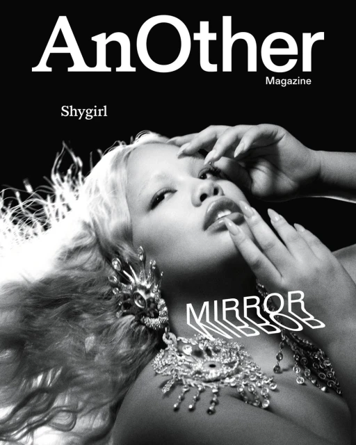 Magazine cover featuring a light-skinned woman with blonde hair, large earrings, and a necklace against a dark background.