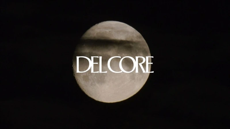 A full moon is partly covered by a dark cloud with the text 'DEL CORE' overlapping it against a dark night sky background.