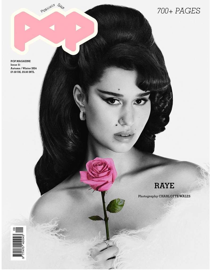 Black and white magazine cover featuring RAYE holding a pink rose, soft feather boa, and dramatic hair and makeup against a light background.