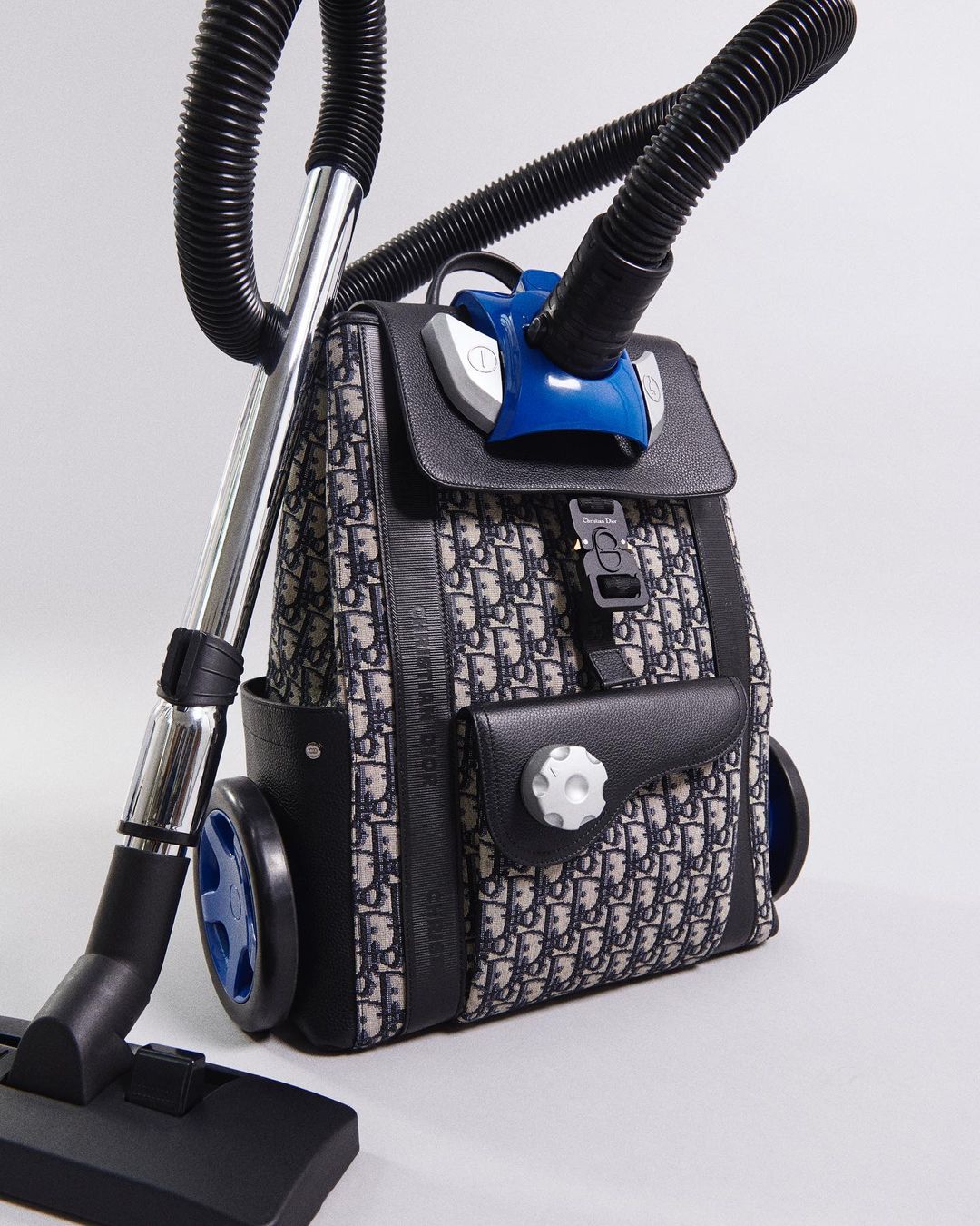 Backpack converted into vacuum cleaner featuring a black and white patterned fabric, integrated wheels and vacuum attachments.