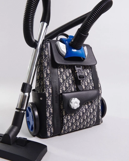 Backpack converted into vacuum cleaner featuring a black and white patterned fabric, integrated wheels and vacuum attachments.