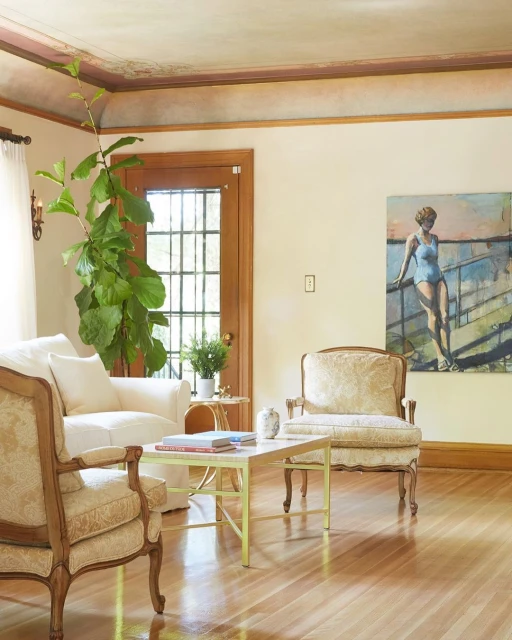 Living room interior with two patterned armchairs, white sofa, coffee table, houseplant, and a painting of a woman in a swimsuit.