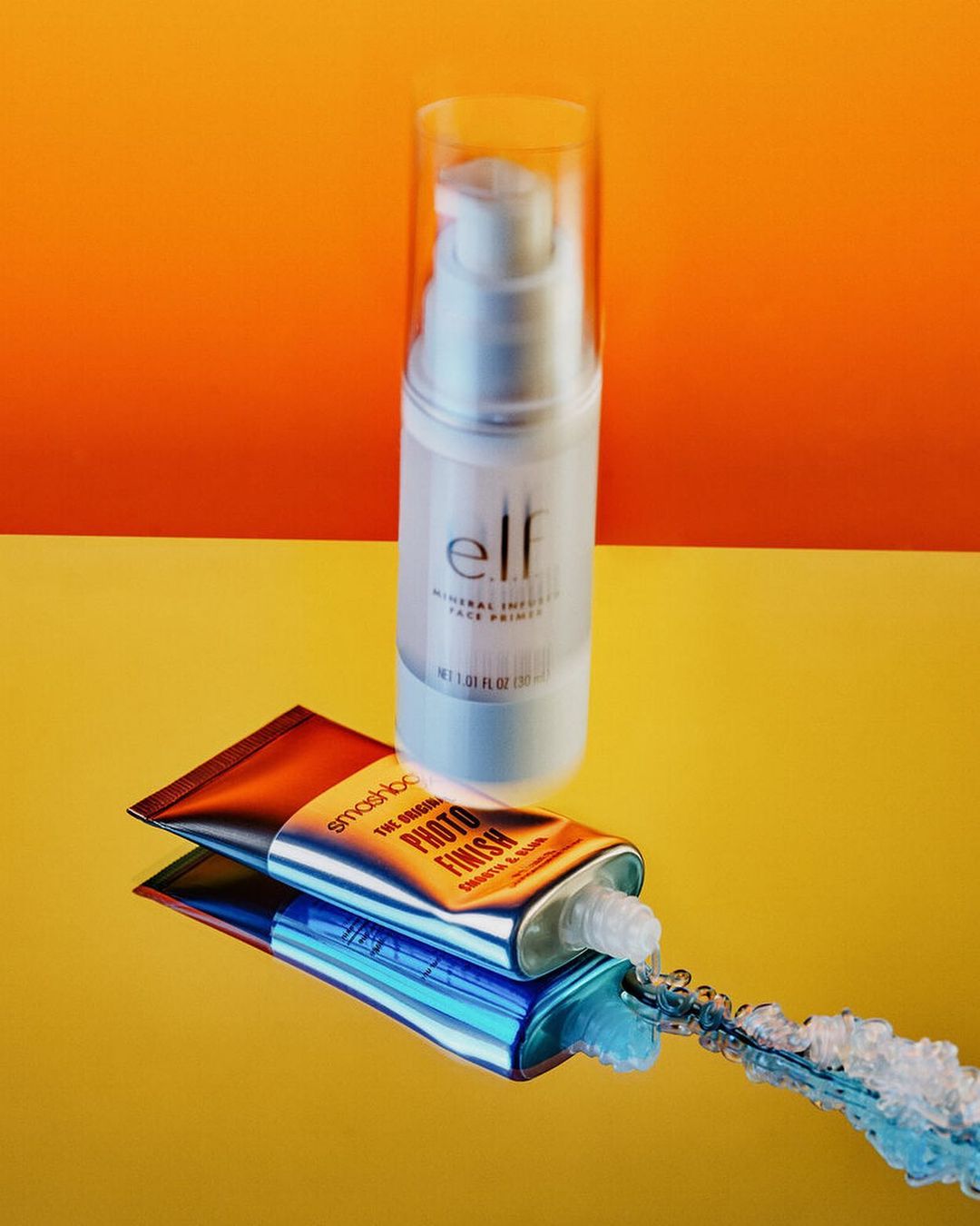 Cosmetics still life: a clear pump bottle of elf mineral infused face primer sits above a tube of Smashbox photo finish primer.