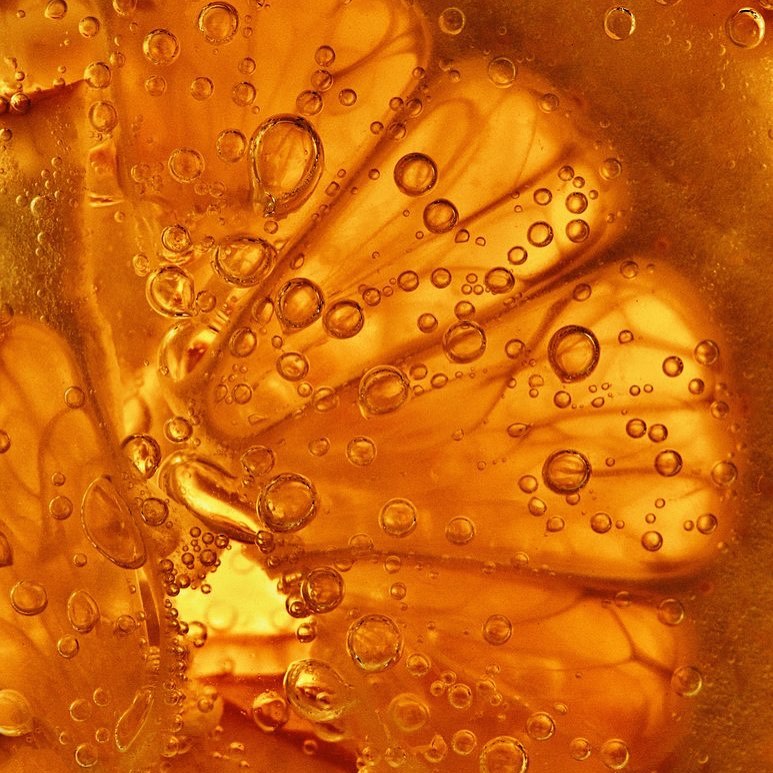 Close-up of an orange slice submerged in liquid with bubbles, showcasing the fruit's texture and vibrant color, creating a refreshing and appetizing image.