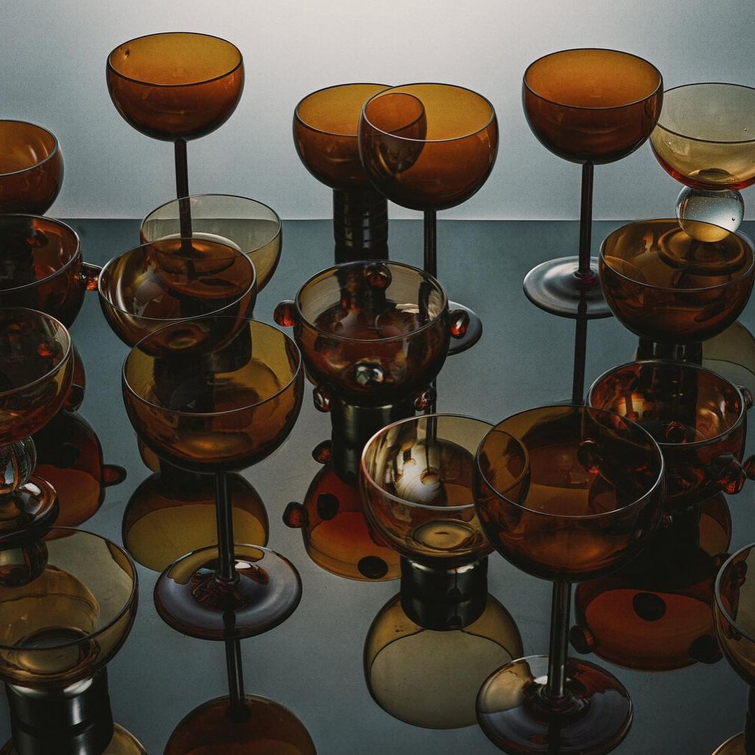 Still life with amber glassware set against a light gray background and surface, creating a warm, elegant, and reflective display.