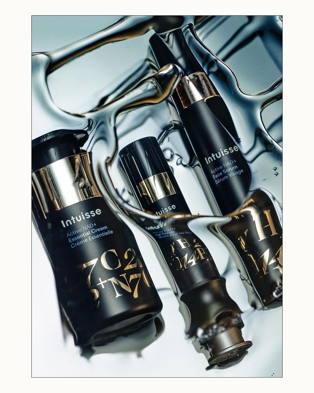 Cosmetic product photography features sleek, black Intuisse bottles with gold accents, set against a reflective, water-like surface. Beauty, skincare.