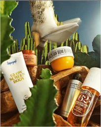 Commercial still life featuring beauty products and a rhinestone-embellished boot among cacti and wooden elements