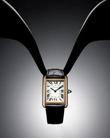 Elegant gold-tone wristwatch with a black leather strap is displayed on a graduated grey background with dark bands, fashion time.