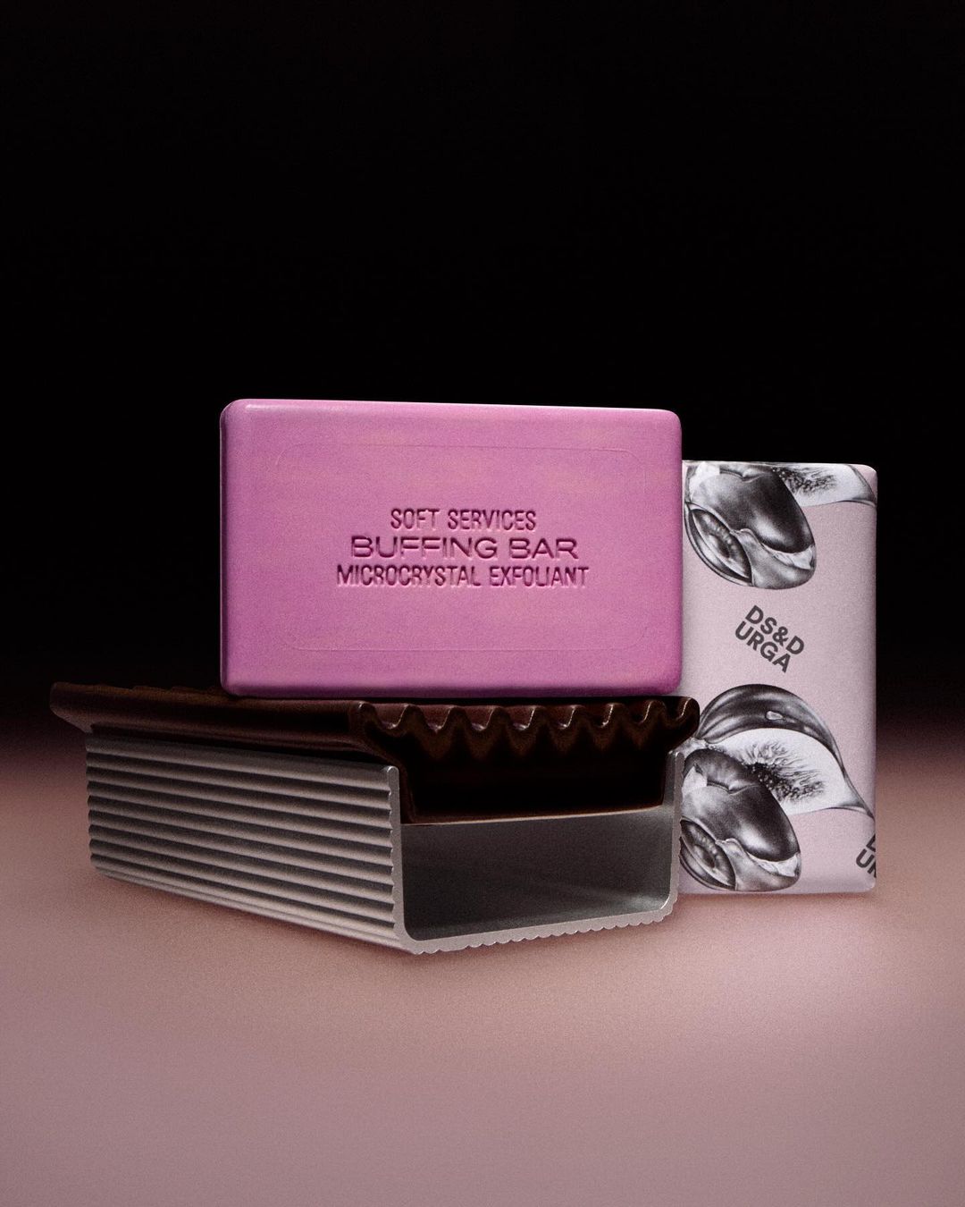 Three bars of different coloured bar soaps, including pink, white, and brown. The bars are stacked on top of one another.