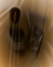 High-angle view of Saint Laurent heels captured with soft motion blur against a warm textured background by Chelsie Craig