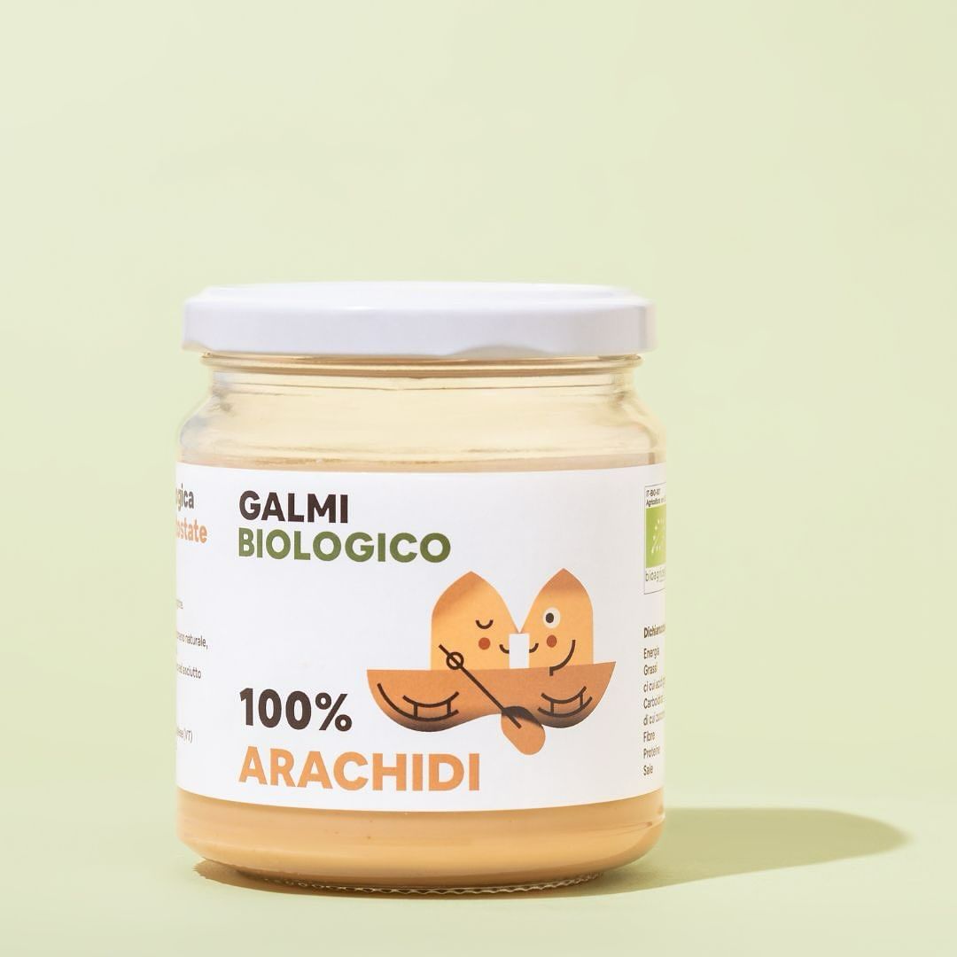Close-up of a clear jar of peanut butter with a white lid and a label featuring a cartoon boat with two peanut characters.