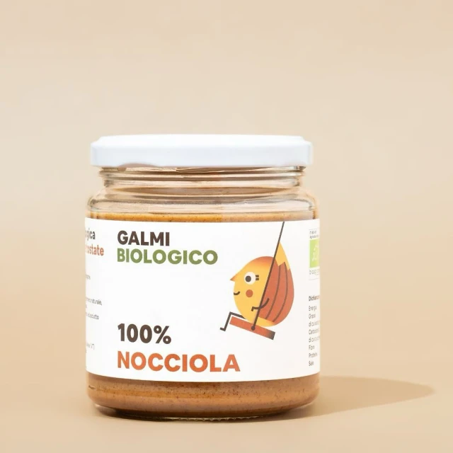 Close-up of a glass jar filled with hazelnut spread and a white lid, showcasing a cute cartoon hazelnut character on the label.