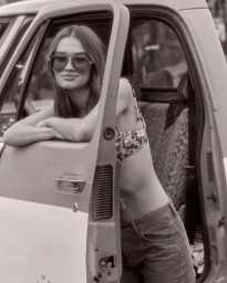 A woman wearing sunglasses leans on the open door of a pickup truck in New York, directed by Child.