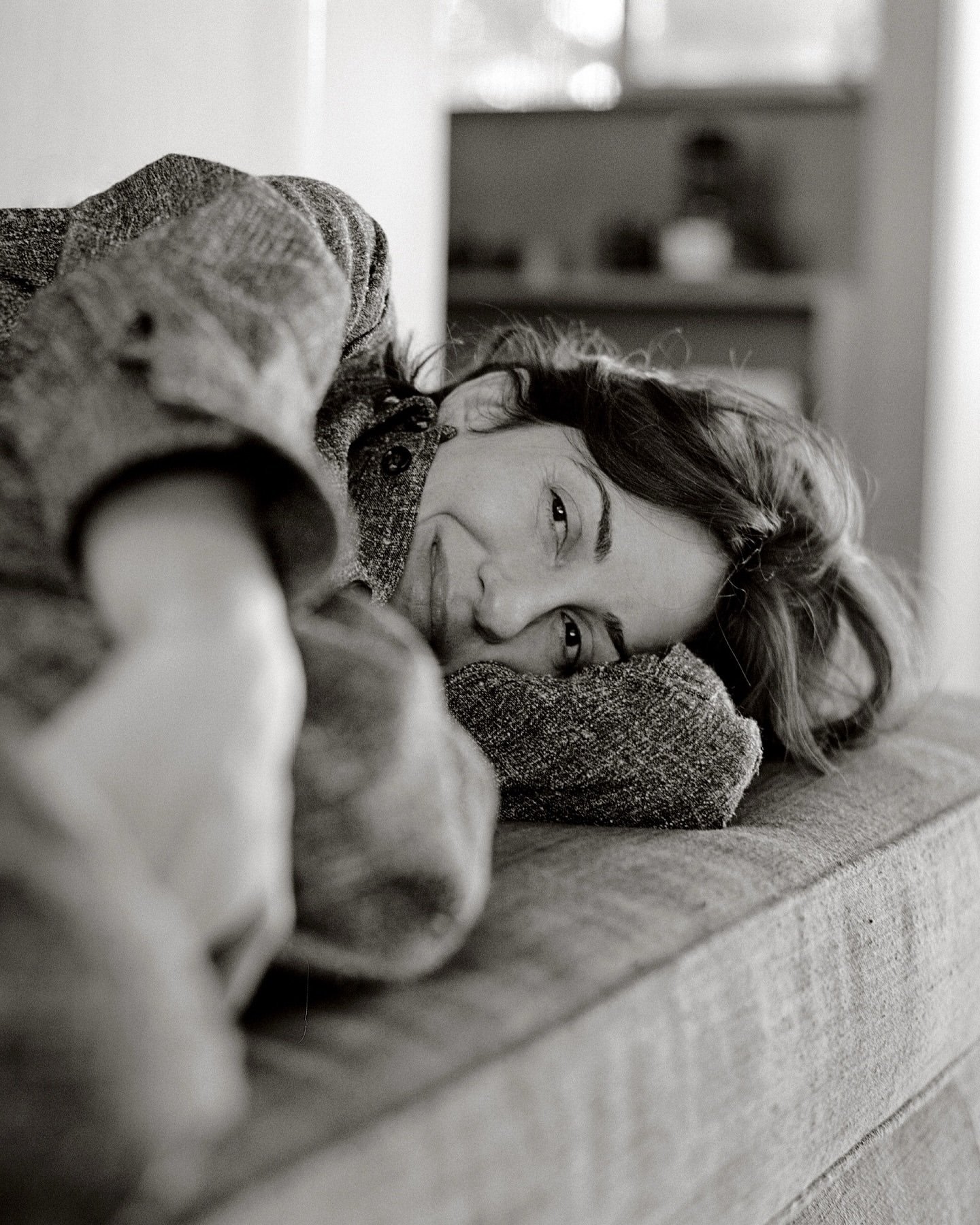 Monochrome portrait of a woman resting her head on a textured upholstered couch, captured by photographer Chloe Chippendale.