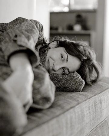 Monochrome portrait of a woman resting her head on a textured upholstered couch, captured by photographer Chloe Chippendale.
