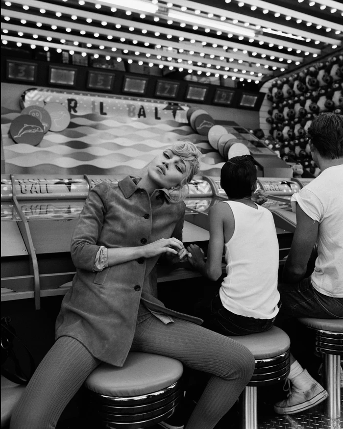 Black and white portrait of a blonde woman seated at a carnival booth by photographer Chloe Chippendale in Paris.