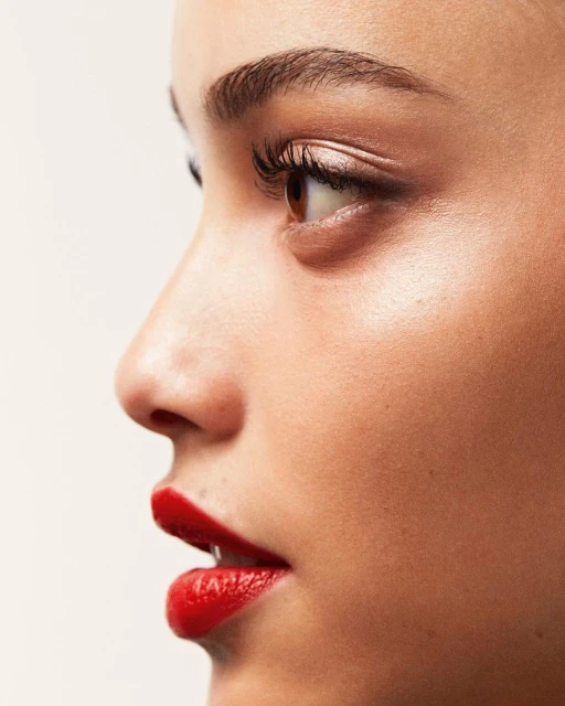 Close-up studio shot of a fair-skinned adult female with red lipstick. The model's profile highlights her makeup and natural features.