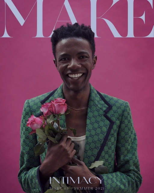 Magazine cover featuring a smiling adult male holding a bouquet of pink roses, wearing a Gucci blazer against a pink background.