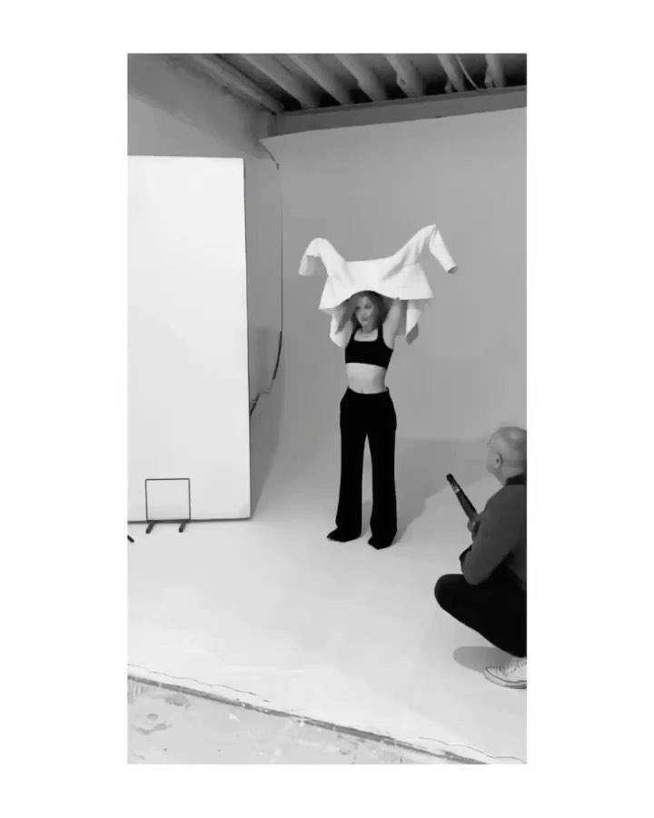 Behind-the-scenes photo by Chloe Mallett in New York showing a model taking off a white jacket in a studio.