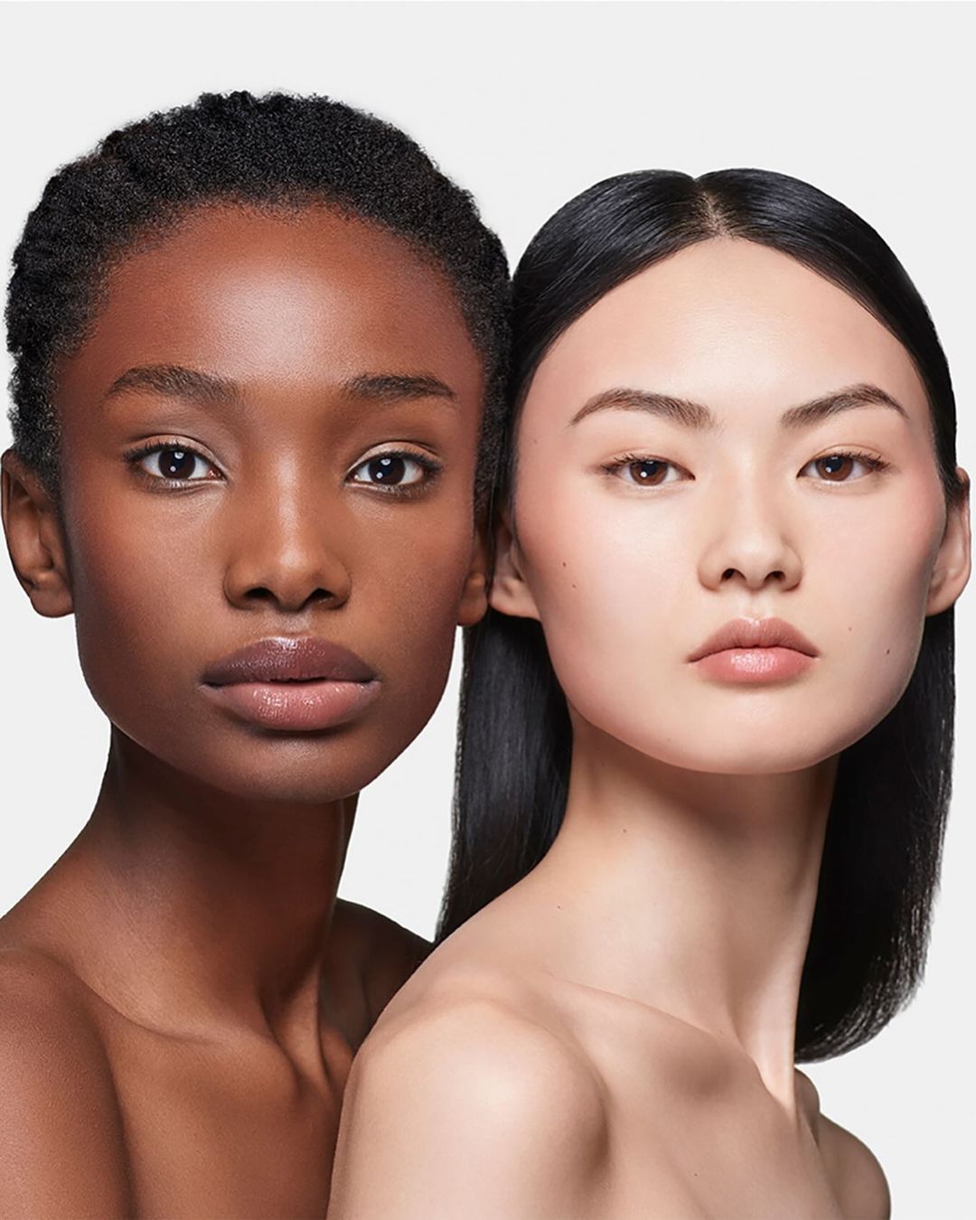 Close-up portrait of two adult women with different skin tones posing in a studio. Beauty, skincare and cosmetic concept.