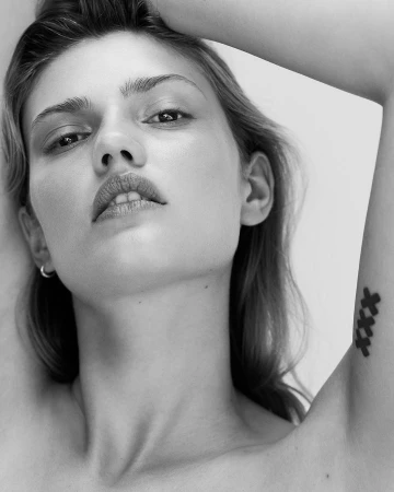 Close-up portrait of a woman with a tattoo on her arm, shot by Chris & Cory in Dusseldorf against a plain white studio background.