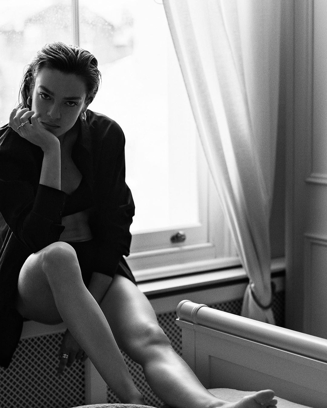 Black and white portrait of a woman sitting by a window in a dark shirt, photographed by Chris & Cory in Düsseldorf