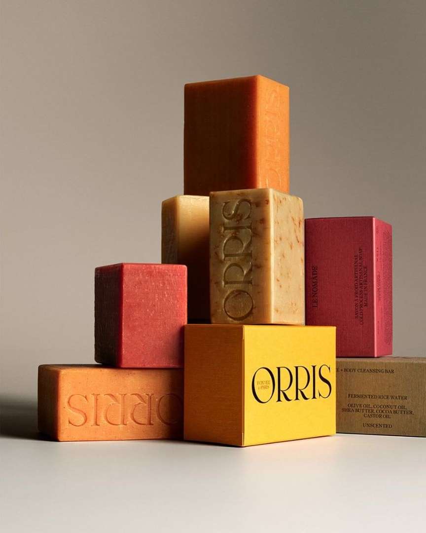 Stacked assortment of colorful Orris body cleansing soap bars in a studio setting, showcasing the brand's minimalist packaging and design.