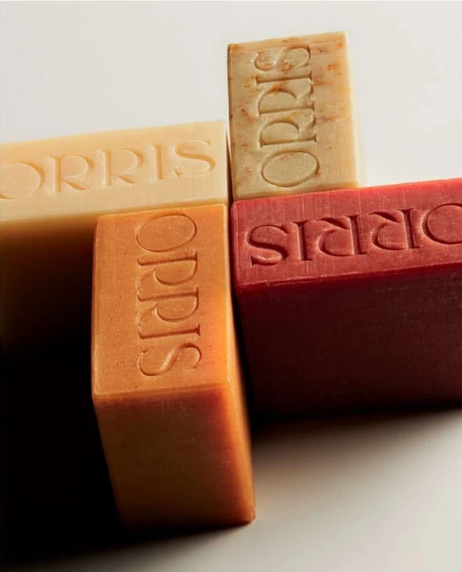 Four bars of ORRIS soaps in different colors stacked together with the brand name embossed, creating a visually appealing composition.