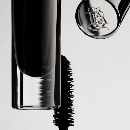 Close-up of a mascara tube and applicator with branding on a white backdrop, showcasing beauty and cosmetic product.