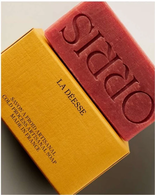 Artisanal soap bar with embossed 'ORRIS' text and its box labeled 'LA DEESSE'. The soap and box create a textured and contrasted image.