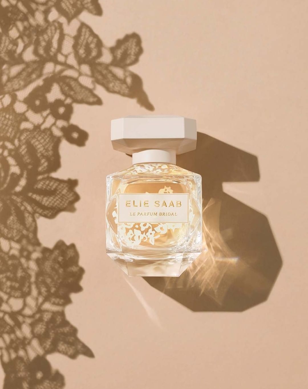 Elegant perfume bottle on peach backdrop with floral shadows, capturing the essence of beauty and sophistication for luxury branding.