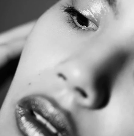 Extreme close-up monochrome portrait of a person face featuring glistening lips and dark glossy eye makeup by Chris & Cory.