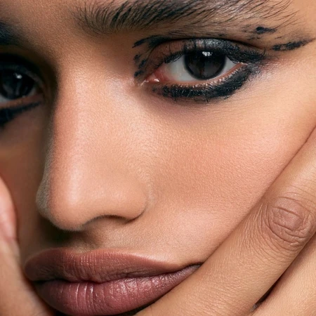 Close-up beauty portrait of a person with dark eyeliner and hand near face photographed by Chris and Cory
