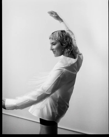 Portrait of a woman wearing a white button-down shirt posing against a plain background photographed by Chris Bernabeo.