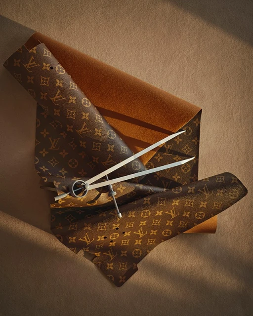 Leather swatches of luxury design with geometric compass-divider resting on top. Brown, tan, silver color palette, and studio lighting.