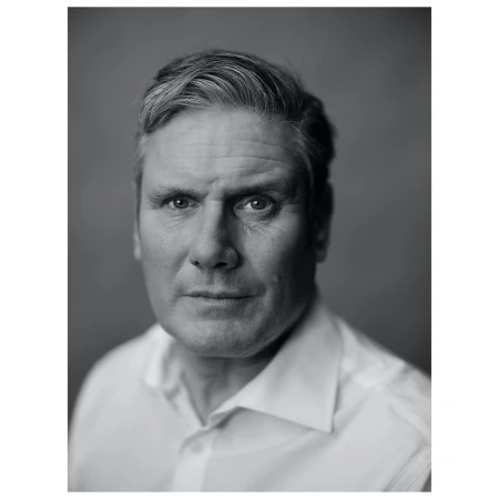 Monochrome portrait of a middle-aged man with graying hair, wearing a white collared shirt, set against a plain gray backdrop.
