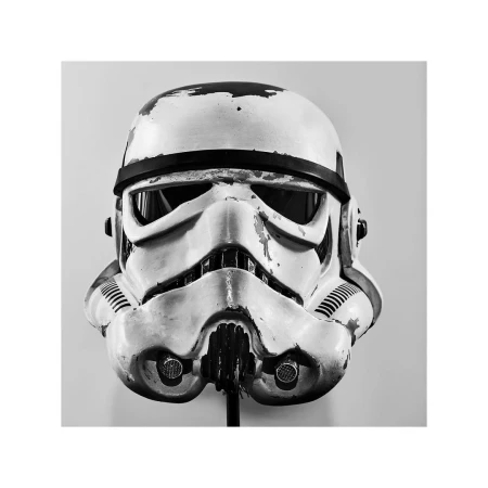 Close-up studio shot of a weathered Stormtrooper helmet on a stand against a grey background, showcasing details of the iconic design.